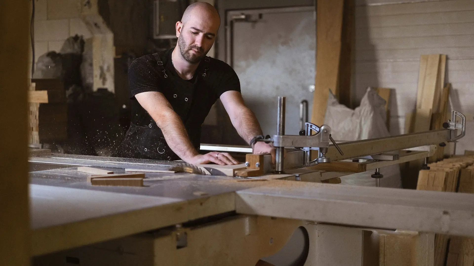 Carpenter cutting timber at a workshop table saw