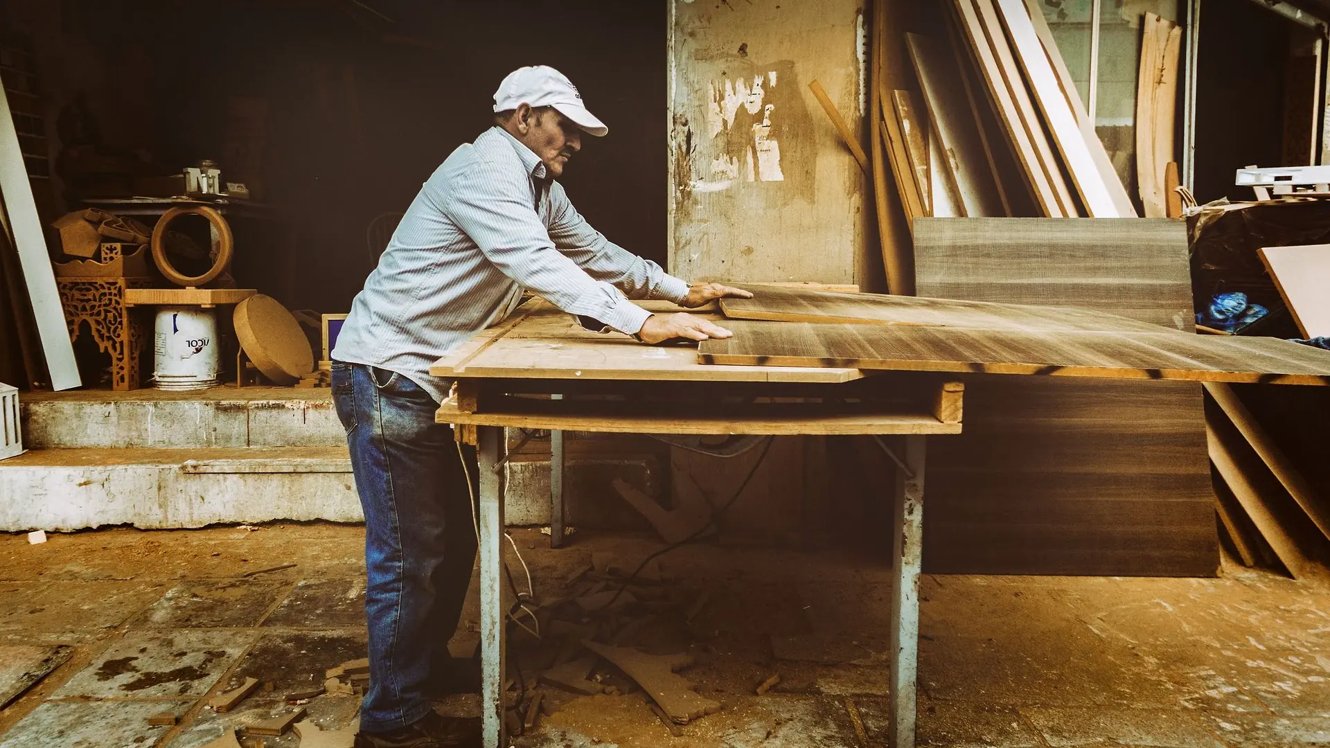 Carpenter cutting a board on a table saw in a bright workshop