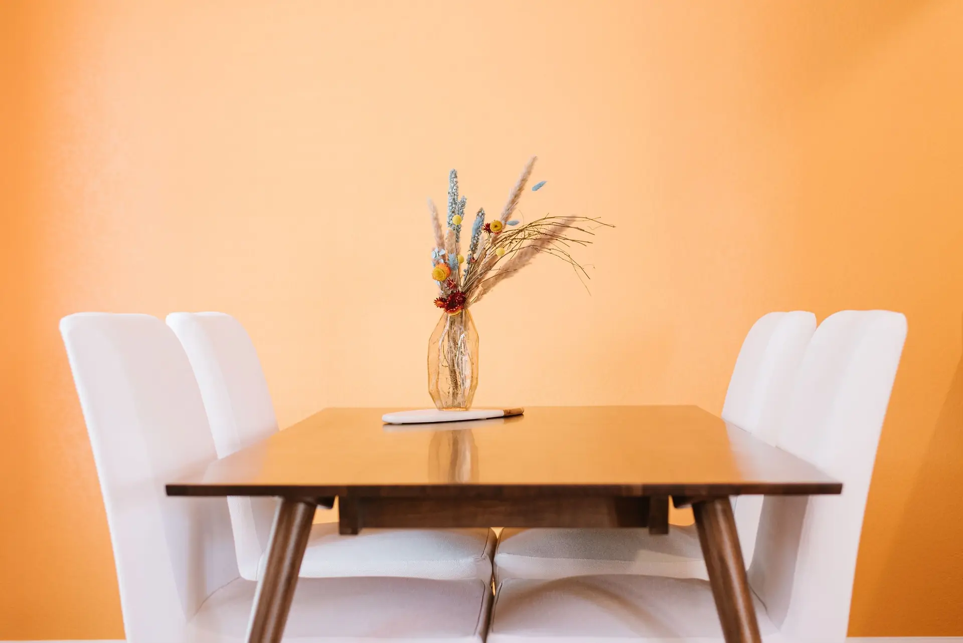 Dining table with flowers and surrounding chairs