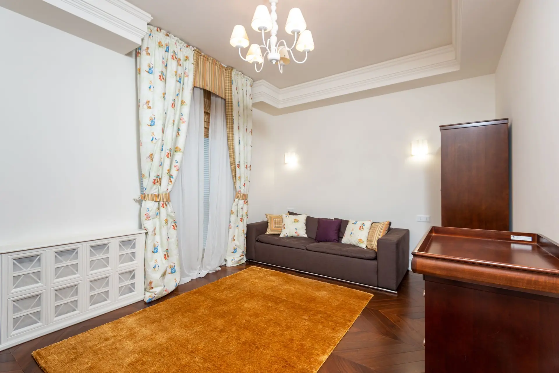 Spacious living room lit by a central chandelier