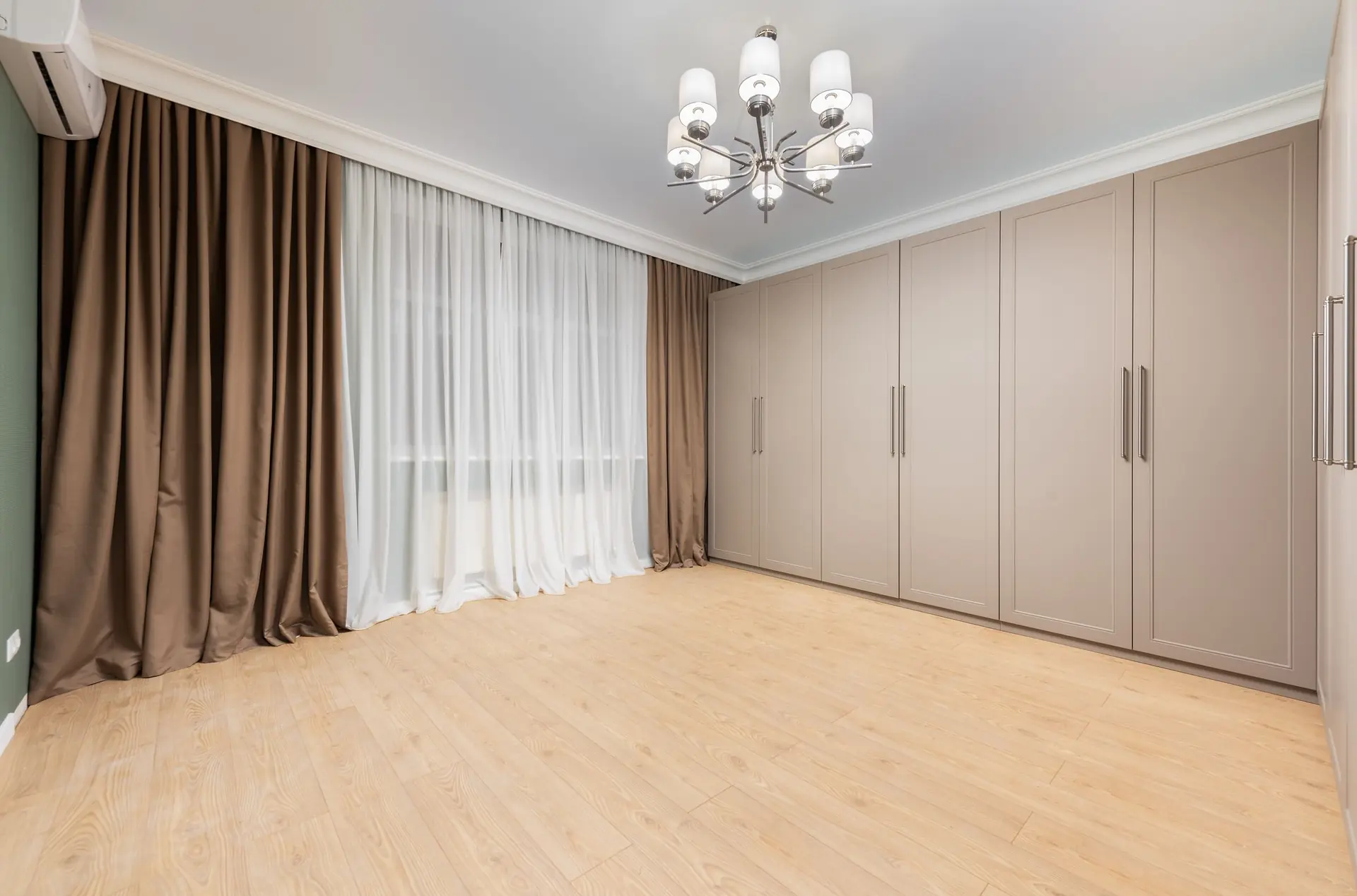 Wardrobe on parquet flooring beneath a chandelier