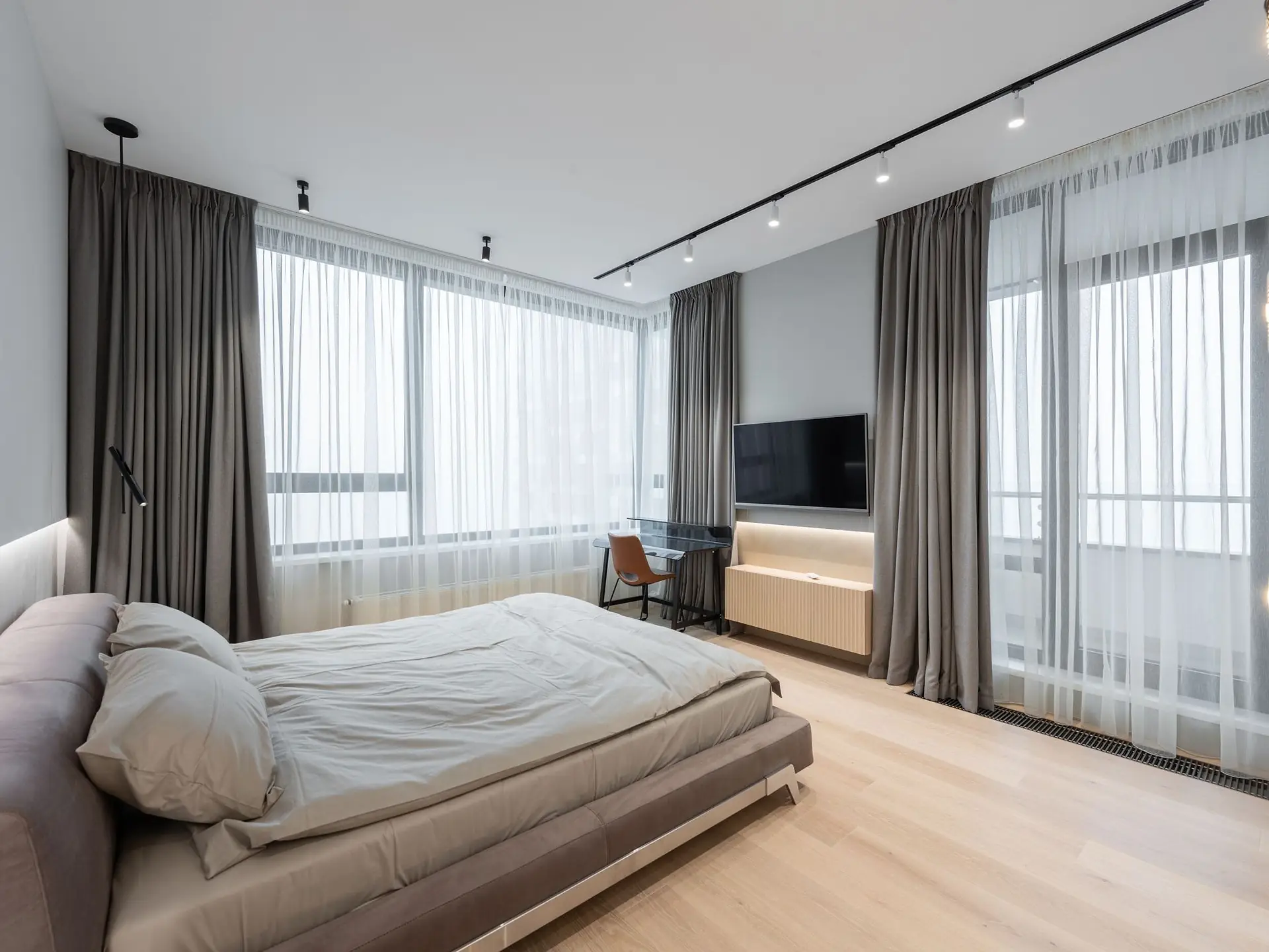 Upholstered bed set against full-height curtains