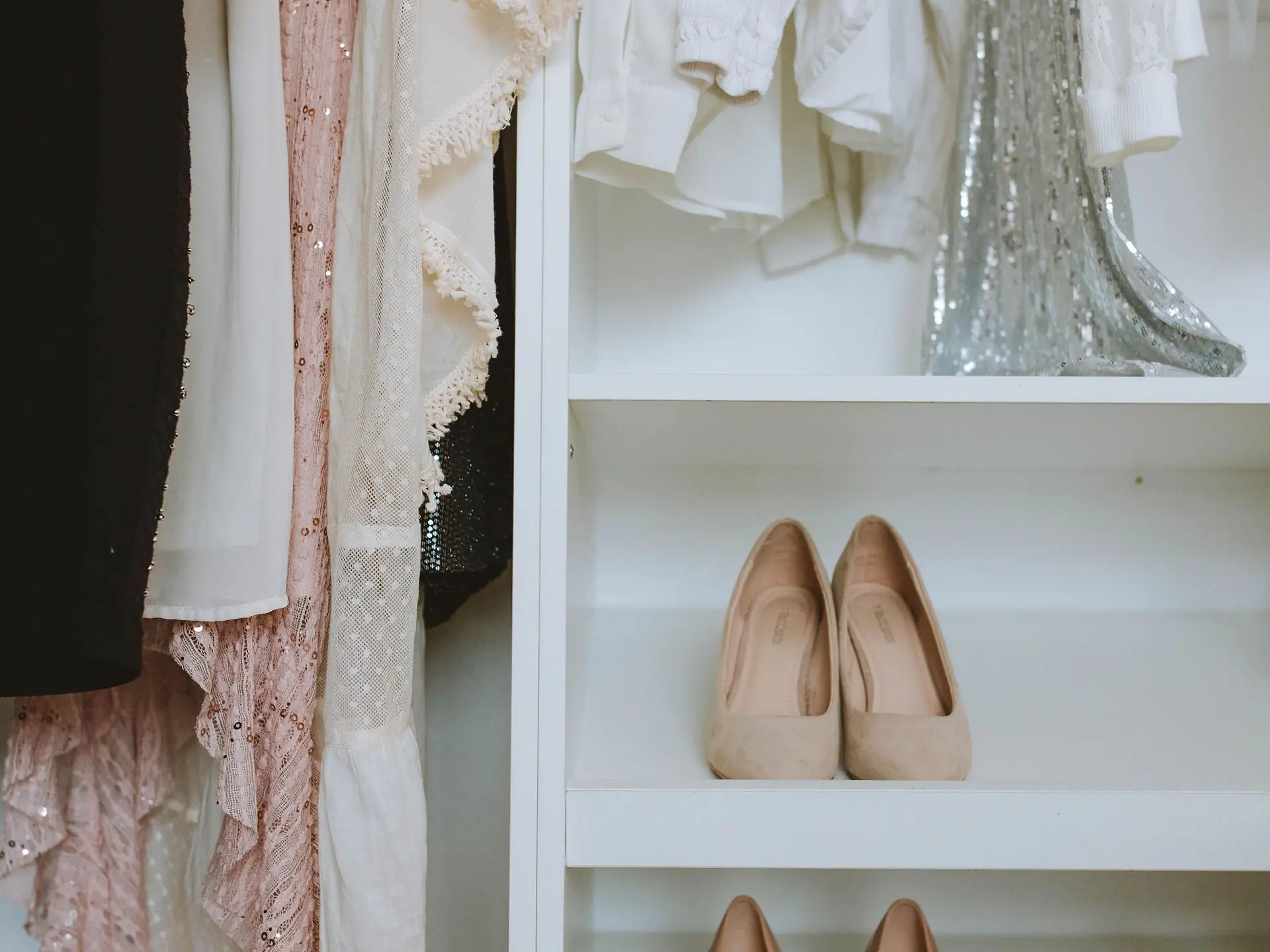 Closet shelving with shoes stored beneath hanging clothes