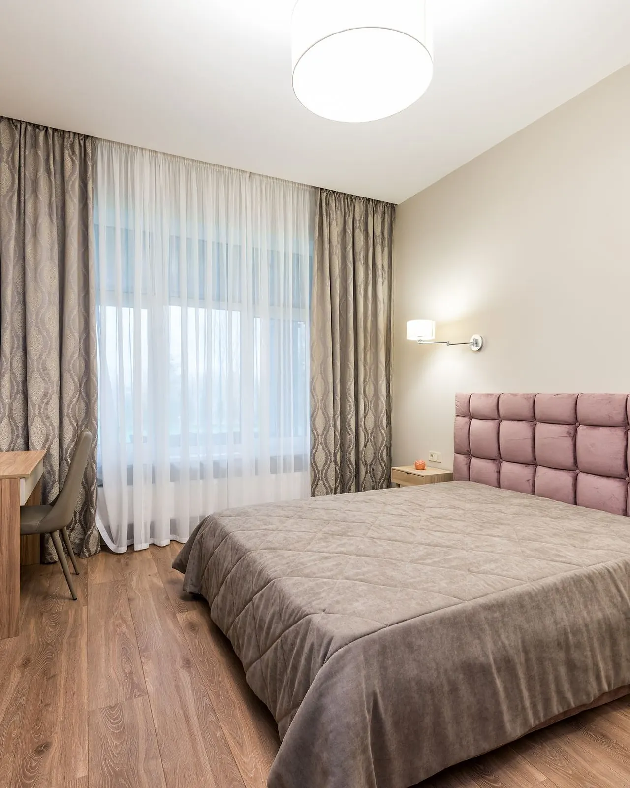 Spacious bedroom with an upholstered brown bed and bedside lighting